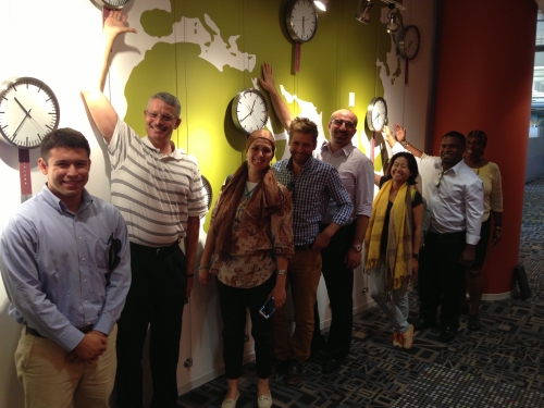 Global Chamber members gathered in front of a world map and a wall of clocks set to different time zones